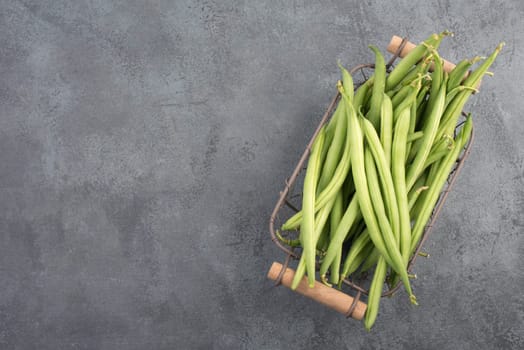 Green string beans on a textured background, empty space for text, fresh vegetables