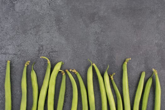 Green string beans on a textured background, empty space for text, fresh vegetables