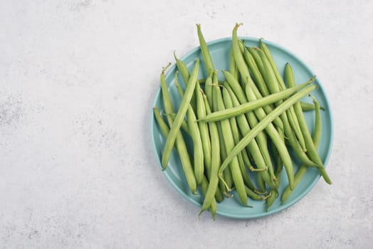 Green string beans on a textured background, empty space for text, fresh vegetables
