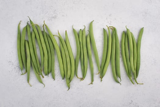 Green string beans on a textured background, empty space for text, fresh vegetables