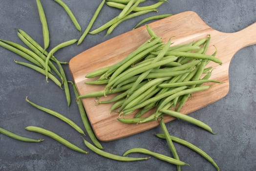 Green string beans on a textured background, empty space for text, fresh vegetables