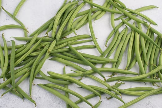 Green string beans on a textured background, empty space for text, fresh vegetables