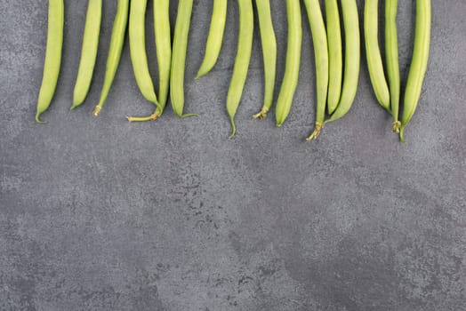 Green string beans on a textured background, empty space for text, fresh vegetables