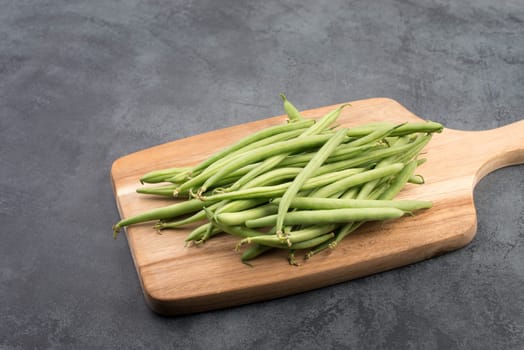 Green string beans on a textured background, empty space for text, fresh vegetables