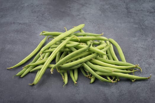 Green string beans on a textured background, empty space for text, fresh vegetables