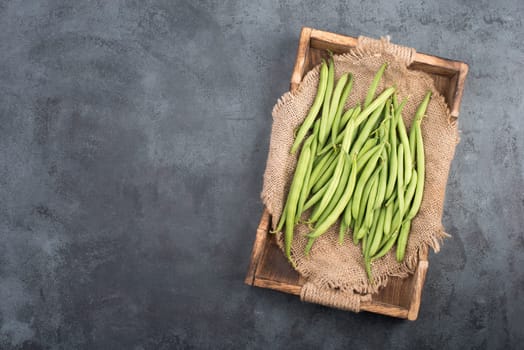 Green string beans on a textured background, empty space for text, fresh vegetables