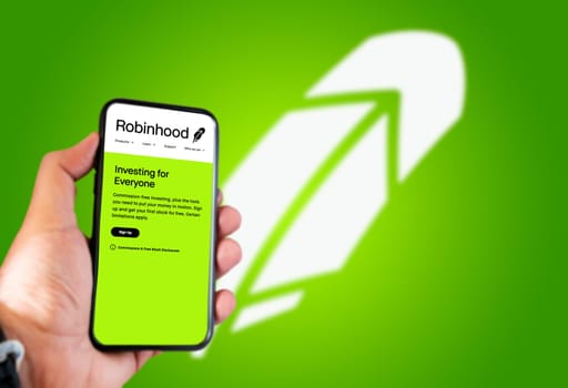 Menlo Park, CA, USA, April 2021: hand holds a smartphone with the Robinhood logo on the screen. Green background with blurred logo. Robinhood is a financial american services company