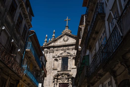 Porto, Portugal: partial view of Igreja de Nossa Senhora da Vitória (Our Lady of Victory Church) and old residential buildings seen from street level, in the afternoon summery light.