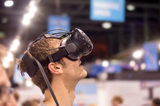 Young man is using virtual reality glasses on an expo