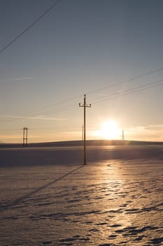 Electrical tower on a snowy field in Austria, sunset scenery