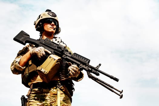 Low angle portrait of US Army Ranger with machinegun on blue sky background looking up. National pride concept