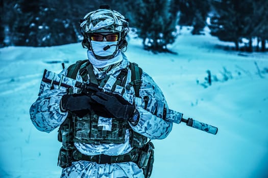 Winter arctic mountains warfare. Action in cold conditions. Trooper with weapons in forest somewhere above the Arctic Circle