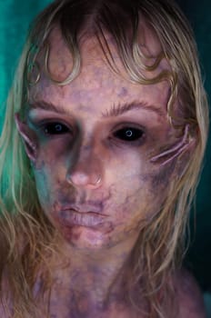 young blond woman infront of black background with scary sfx makeup