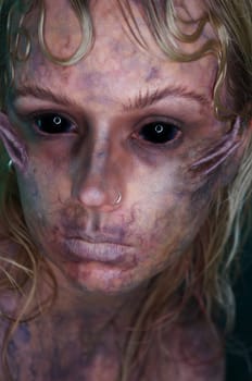 young blond woman infront of black background with scary sfx makeup
