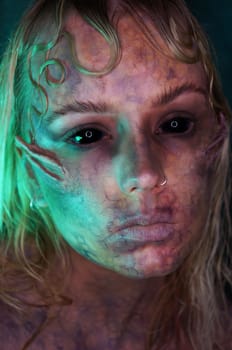 young blond woman infront of black background with scary sfx makeup