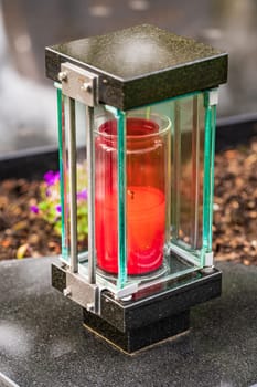 Old damaged grave lantern on a gravestone