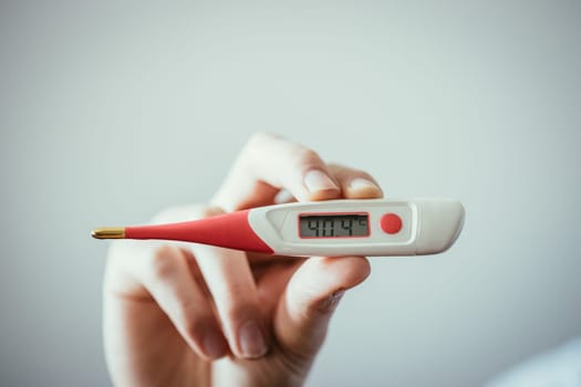 Man is holding a fever thermometer in his hand