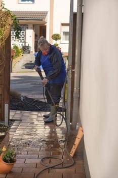 Worker cleaning driveway with gasoline high pressure washer splashing the dirt,professional cleaning services.High pressure cleaning,lower body.