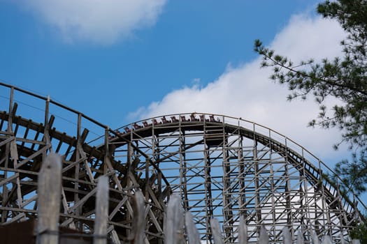Unrecognizable persons on a roller coaster in an amusement park.