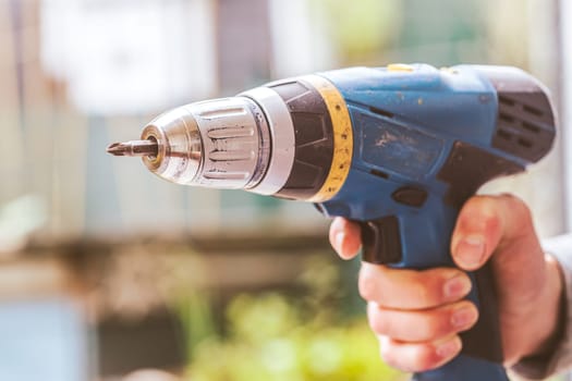 Do it yourself home handyman is holding a cordless screwdriver, outdoors