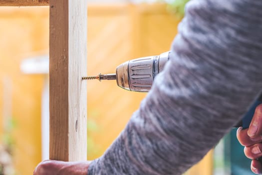 Do it yourself home handyman is using a cordless screwdriver for screwing