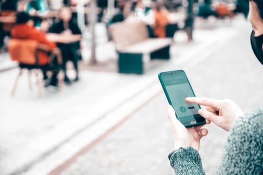 Vaccinated person using immunization certificate on smartphone at the restaurant or terrace.