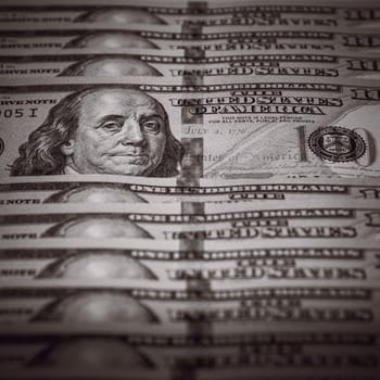 One hundred dollar bills are in a row, one stands out, selective focus. Style black and white.