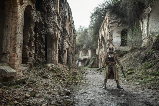 Nuclear post-apocalypse. Sole survivor in tatters and gas mask on the ruins of the destroyed city