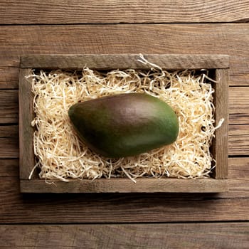 Fresh tropical mango fruit in a wooden delivery box on a wooden background. Healthy eating concept top view flat lay with copy space for some advertisement text