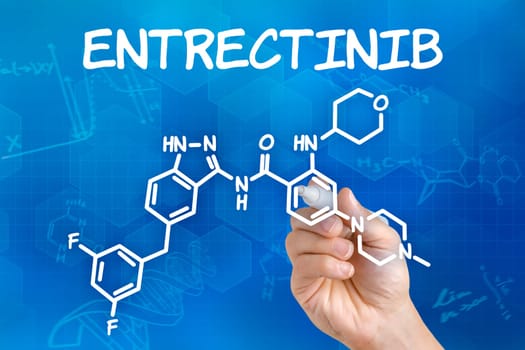 Hand with pen drawing the chemical formula of Entrectinib