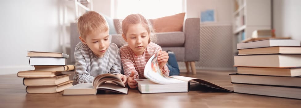 Cute children lying down on the floor and reading books. Concept of family and sibling relationships.