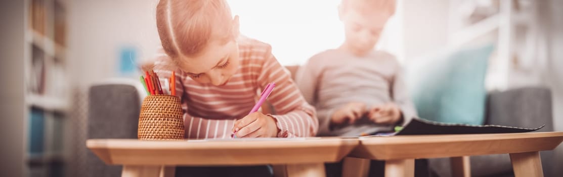 Children playing together with modeling clay and drawing by pencils. Concept of domestic education and family relationship.