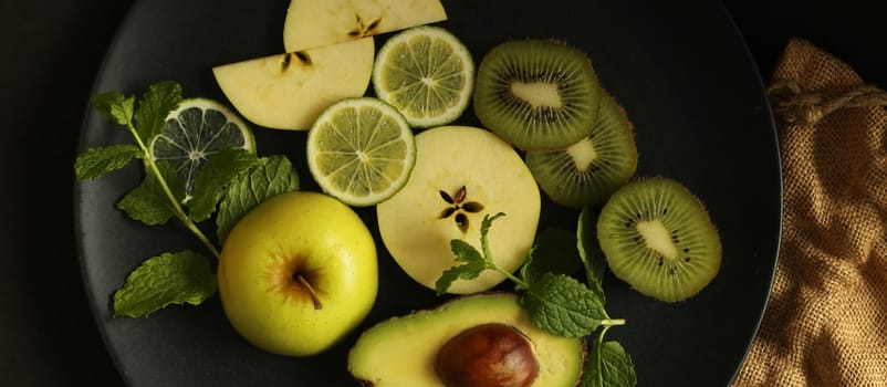 citrus fruits on black background with canvas, top view. Dramatic kitchen with green fruits