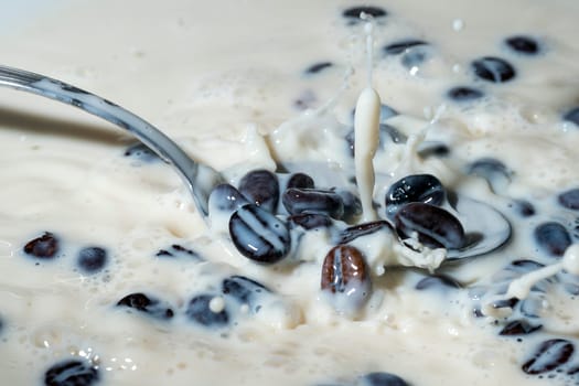 Coffee beans falling on the milk splash. Cup of milk. Concept photography.