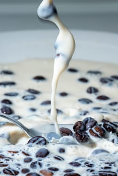 Coffee beans falling on the milk splash. Cup of milk. Concept photography.