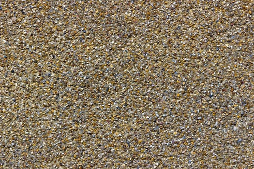 A rough pebble dash covering on an external wall showing small stones of various shapes and colours