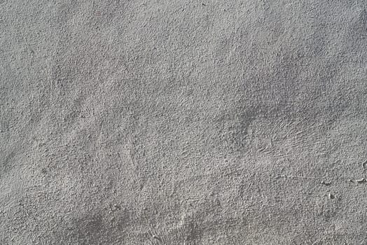 The heavy surface texture of an external wall covered in white plaster.