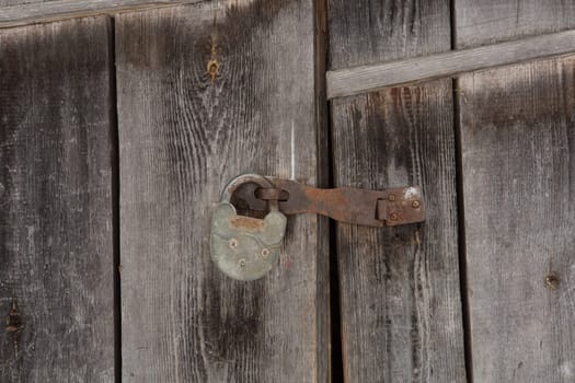 Old vintage metal door lock on wooden door background/texture.