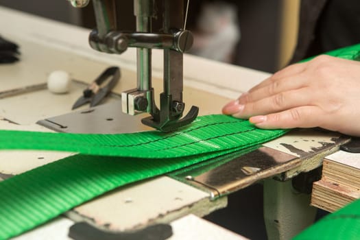 Industrial sewing machine sews a webbing sling. Manufacture of textile slings and tie straps