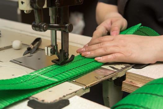 Industrial sewing machine sews a webbing sling. Manufacture of textile slings and tie straps