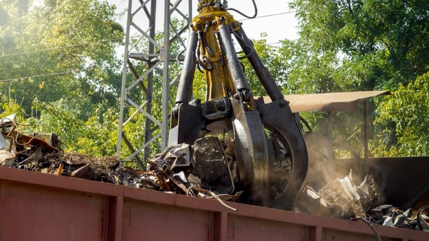 Photo of metal gripper crushing and destroying old metal pieces on junkyard