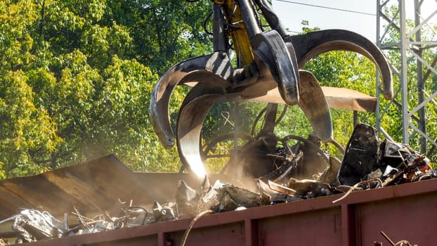 Claw gripper working on metal scrapyard with old rusty pieces