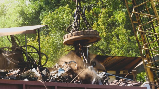 Photo of industrial electric magnet lifting metal details and part on the junkyard