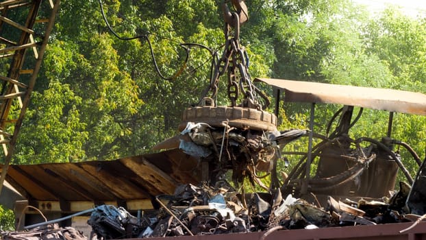 Electric magnet sorting metal waste from other rubbish on scrapyard