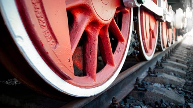 Closeup image of steam power train wheels on rails at railway station