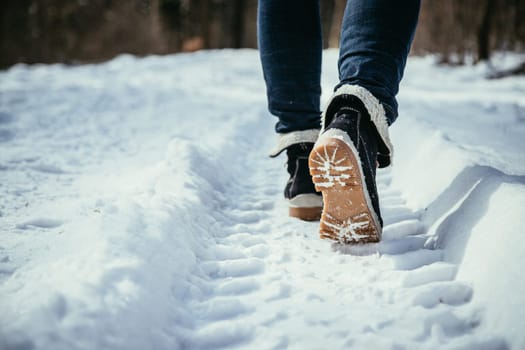 Girl in blue jeans is hiking in the wintertime, legs and shoes
