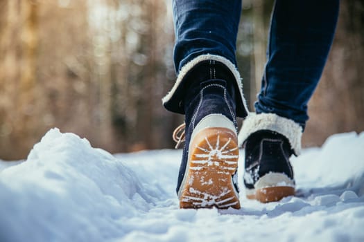 Girl in blue jeans is hiking in the wintertime, legs and shoes
