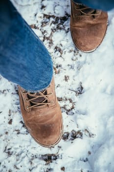 Man in blue jeans is hiking in the wintertime, legs and shoes