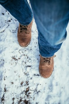 Man in blue jeans is hiking in the wintertime, legs and shoes