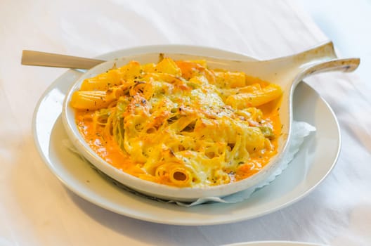 Pasta baked with cheese in a white bowl.
